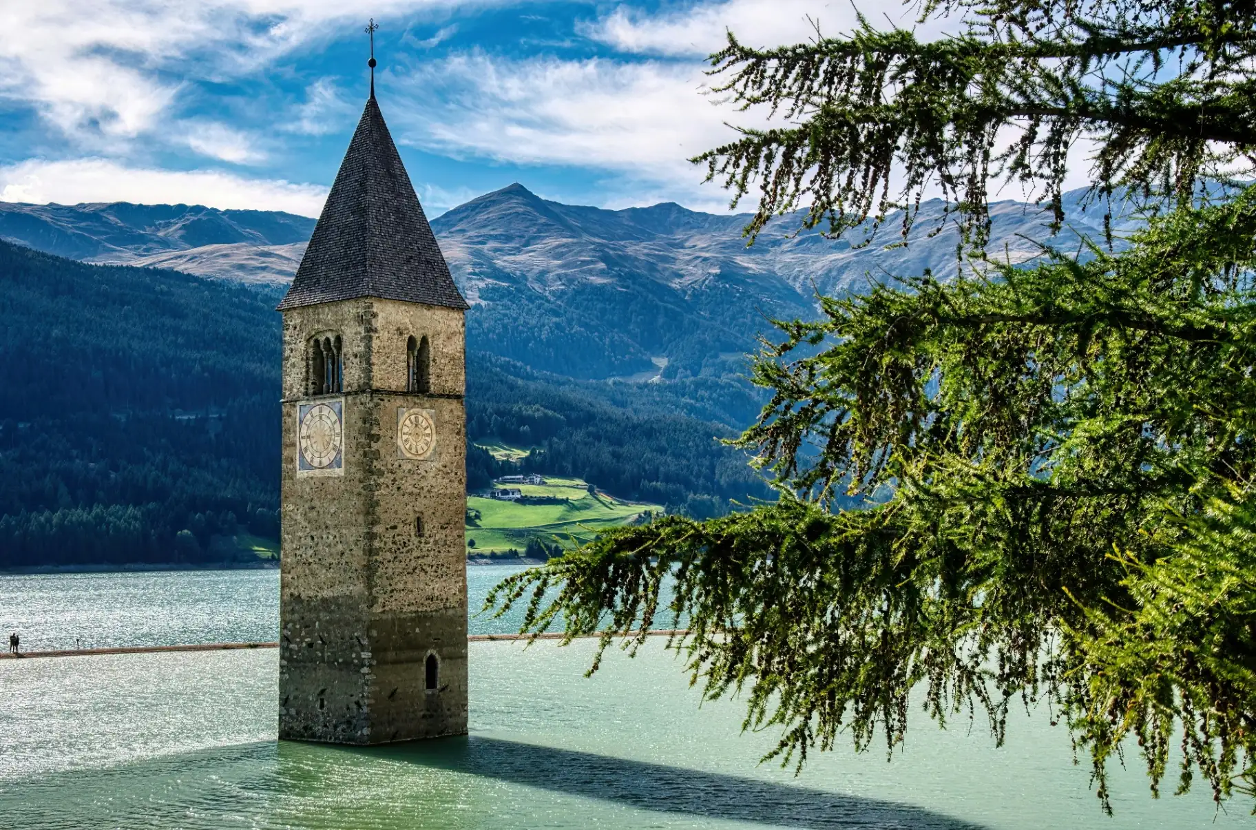Reschensee mit versunkenem Kirchturm und Radfahrerin